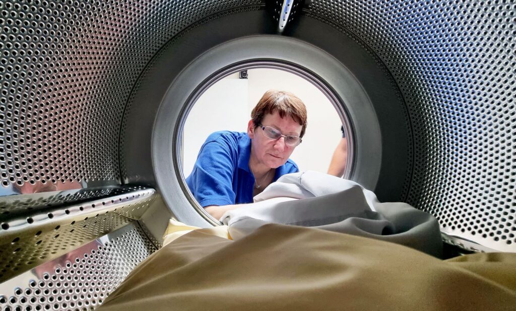 The inside of a laundry machine drum, looking out at an employee