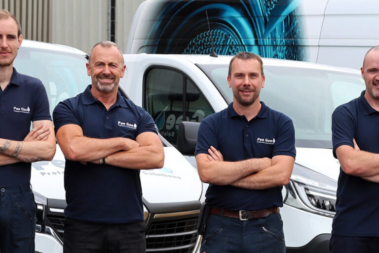 four men with arms folded in front of vans