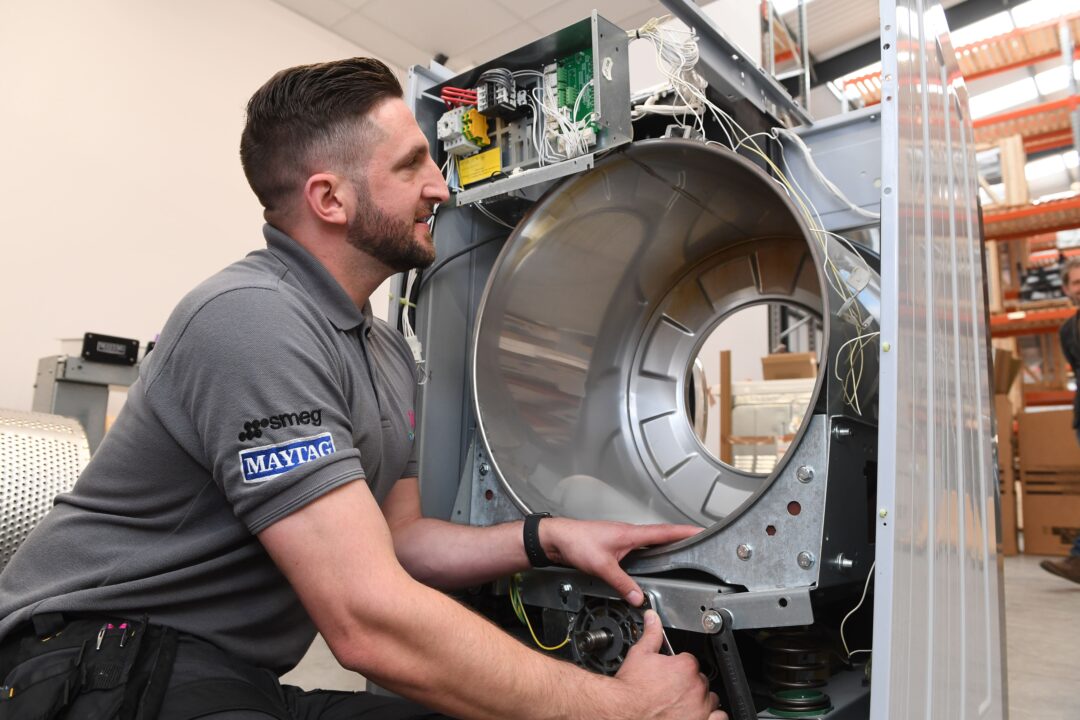 An engineer mending a broken commercial laundry machine.