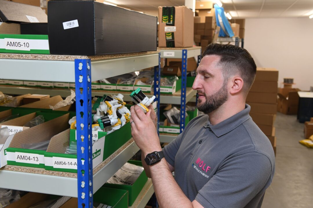 A warehouse worker looking at a commercial laundry machine part.