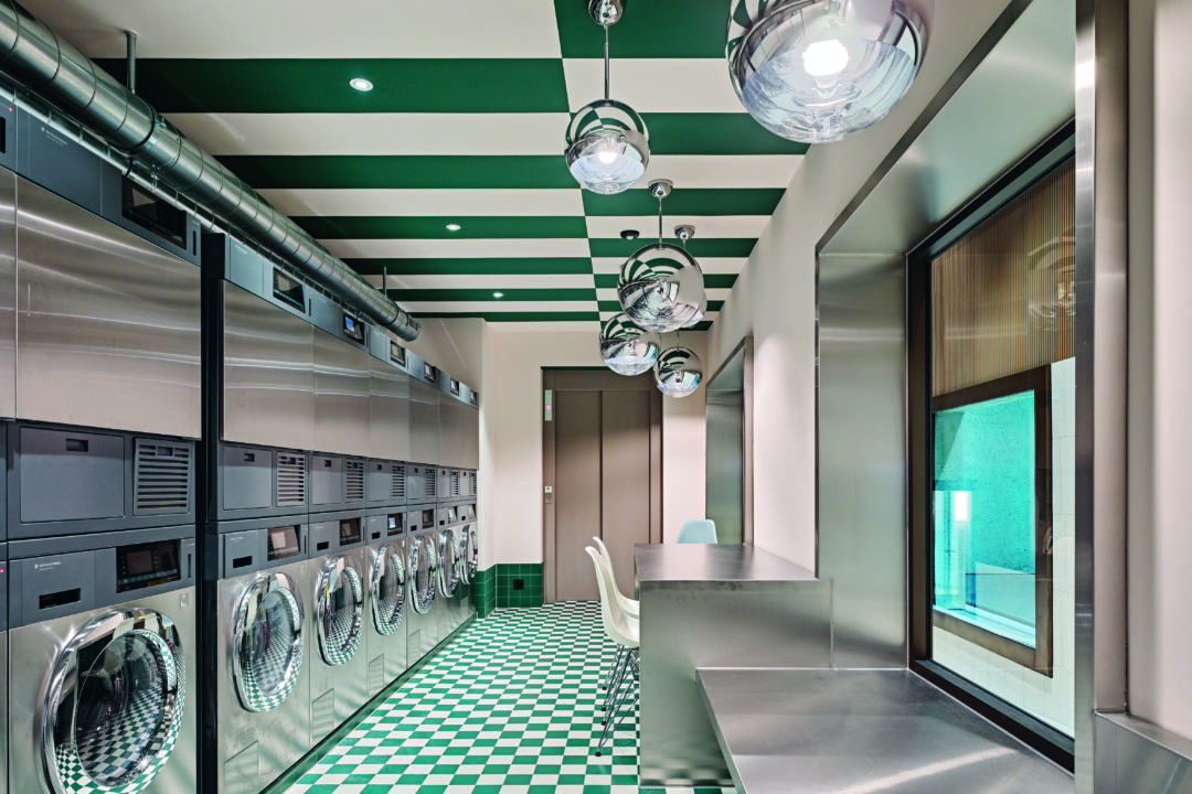 A row of stainless-steel stacked washer/dryers in a modern laundry room