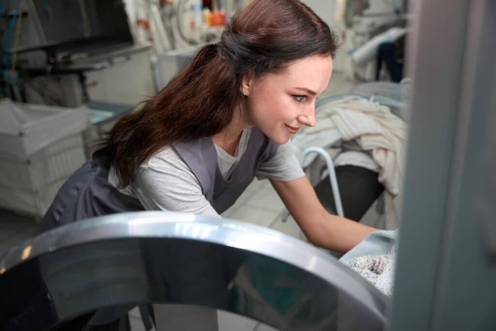 A worker operating commercial laundry equipment.