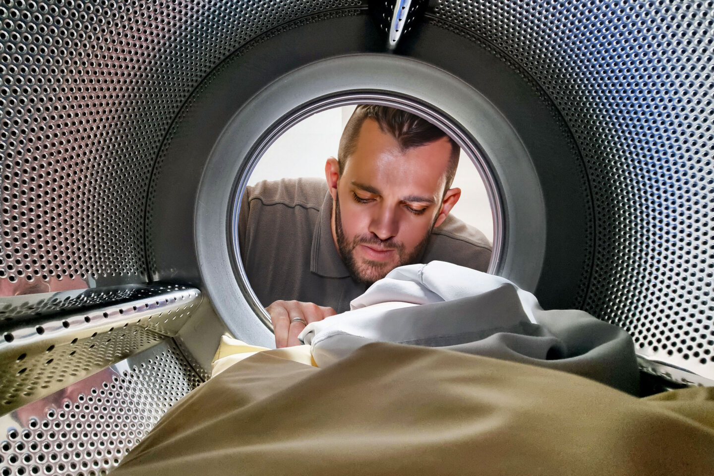 A Wolf Engineer peering into the drum of a commercial washing machine